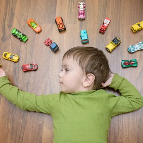 Kid laying on floor with toys | Signature Flooring, Inc